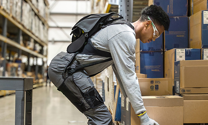 Worker wearing HexArmor’s innovative SafeLift powered exosuit to help lift heavy boxes in a warehouse.