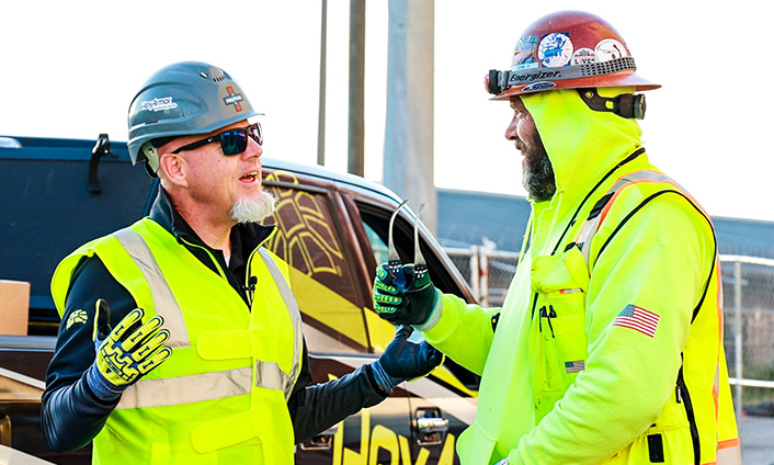 Safety professionals in safety gear talking on a jobsite.