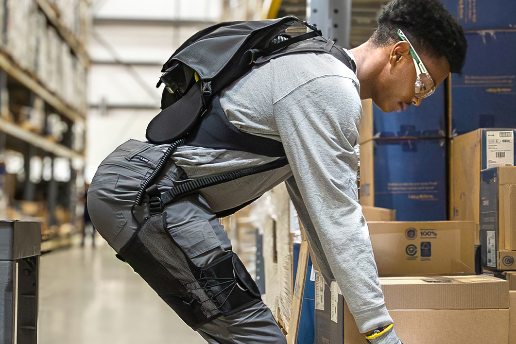 Worker bending to lift a box while wearing the SafeLift™ exosuit.
